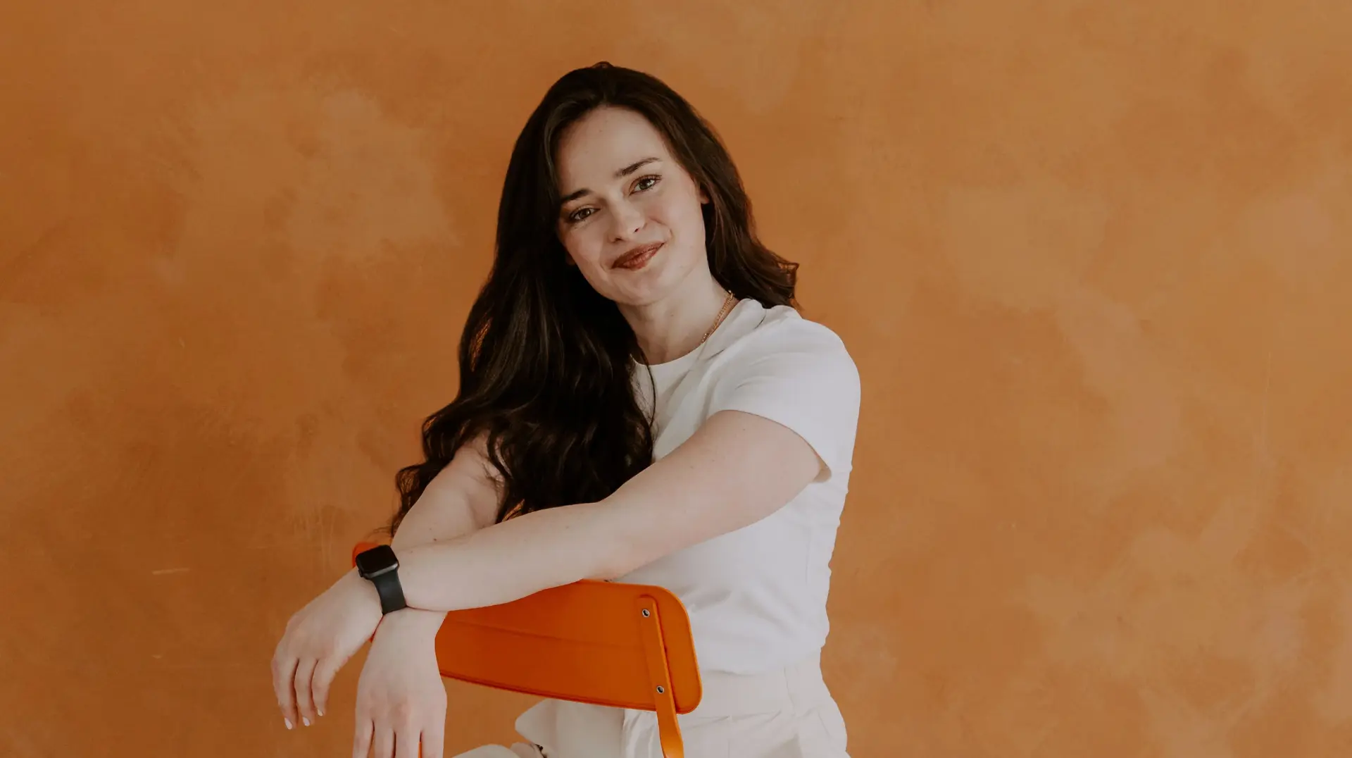 Kat seated against an orange backdrop